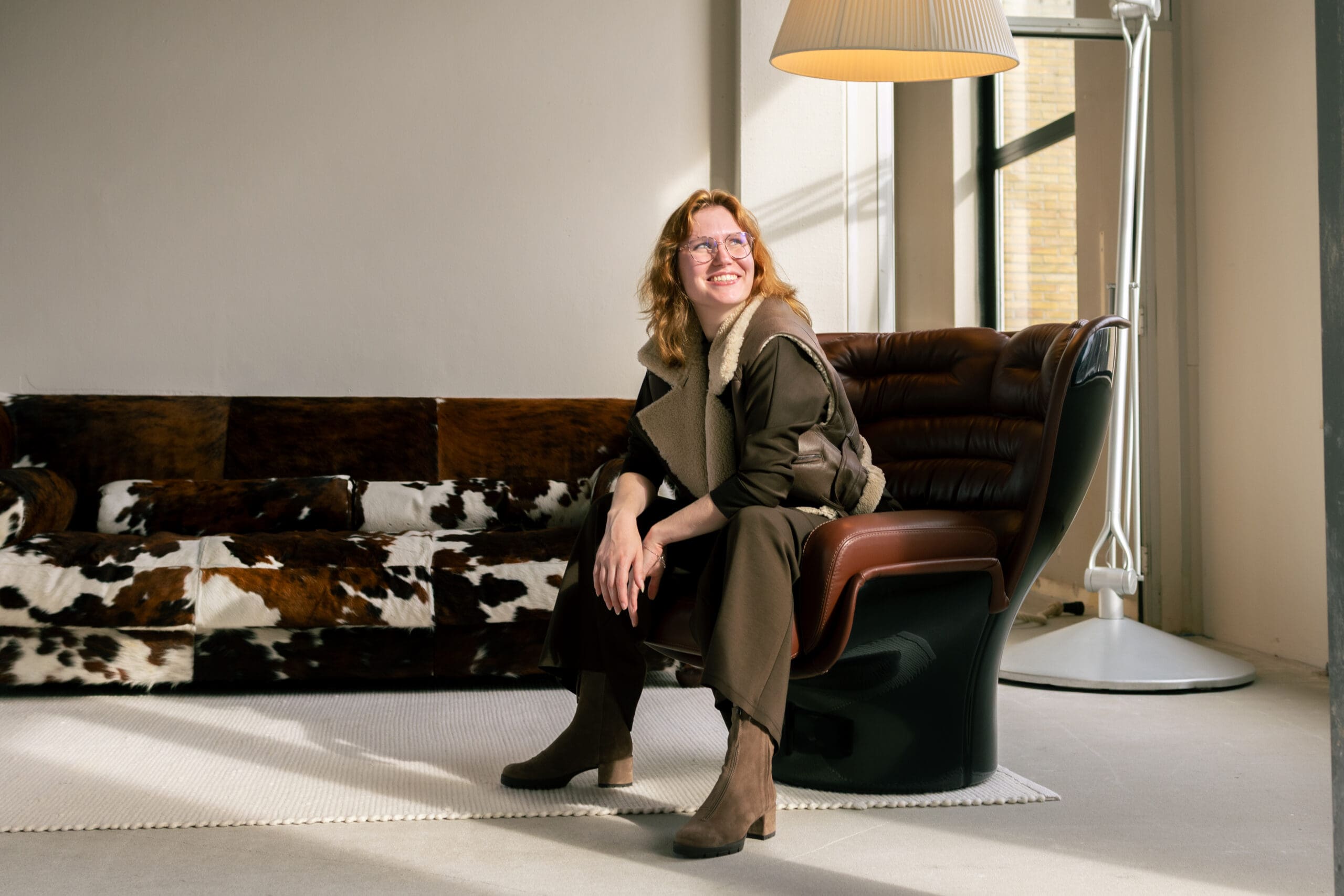 Vrouwelijke ondernemer die in een lerenstoel zit en lacht